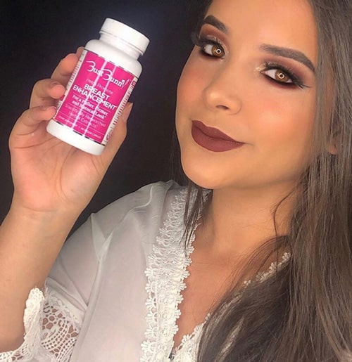 woman holds up Bust Bunny Breast Enhancement pills