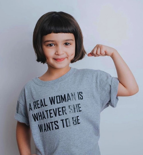 small girl in a t-shirt written “a real woman is whatever she wants to be”
