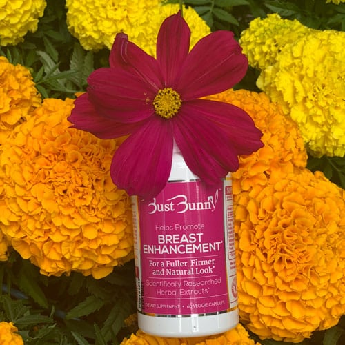 bottle of Bust Bunny’s breast enhancement pills laid on flowers