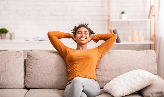 happy black woman relaxing sitting on sofa at home