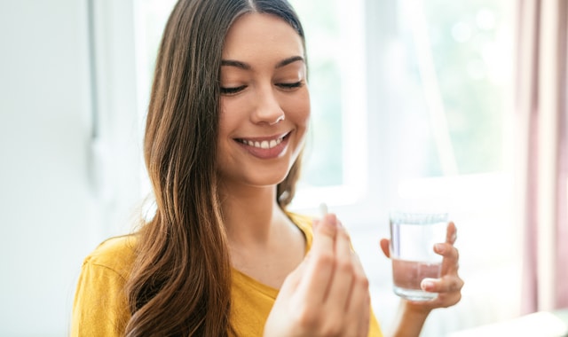 healthy young woman taking herbal supplements