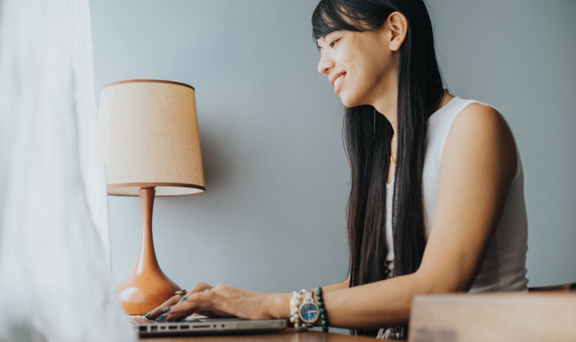 smiling transgender woman using laptop on the table