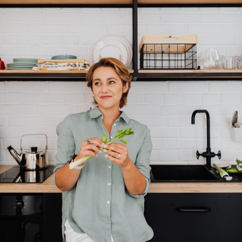 woman eating veggies from kitchen